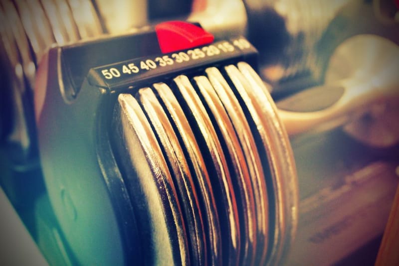Adjustable dial dumbbells on a home gym floor