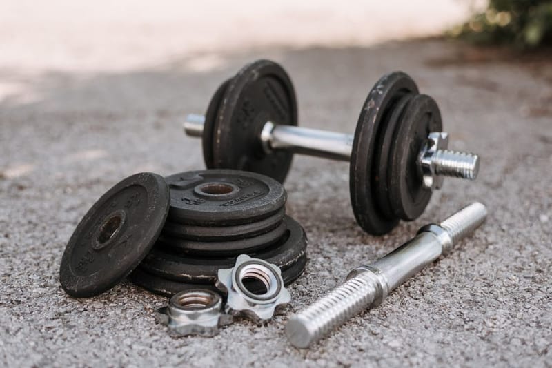 Adjustable dumbbells on the floor of a small home gym