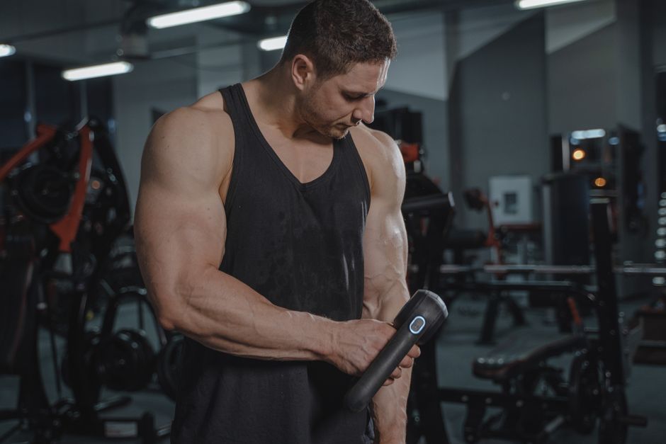 Compact percussion massage gun used on a shoulder after exercise